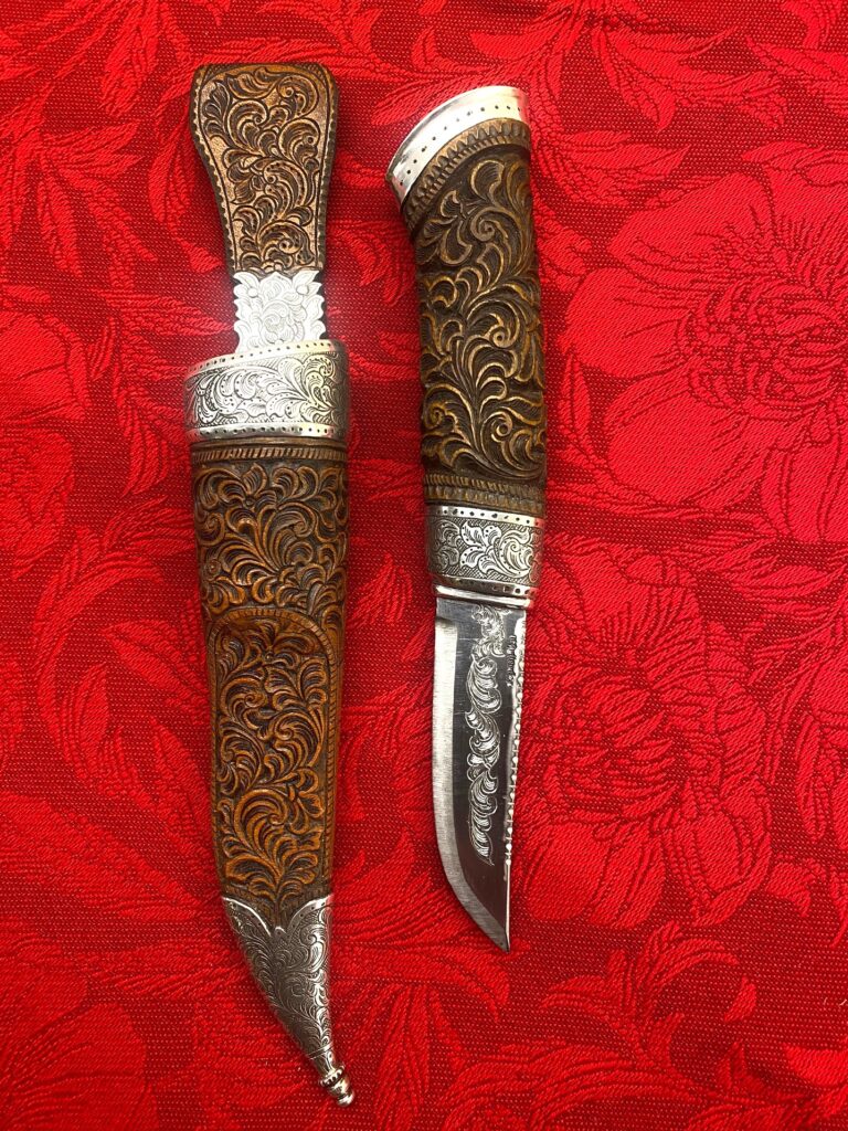 Påkostet kniv med mye sølv. Alle deler er håndlaget og bladet er 3. lags håndsmidd av kjent smed. Holker er håndgravert og i 925 sølv